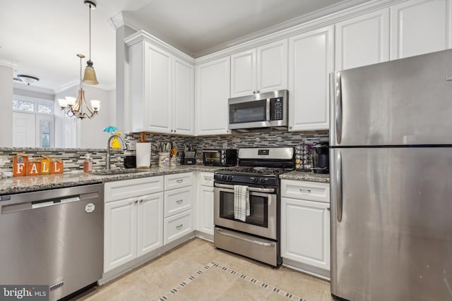 kitchen with tasteful backsplash, light stone counters, white cabinetry, stainless steel appliances, and a chandelier