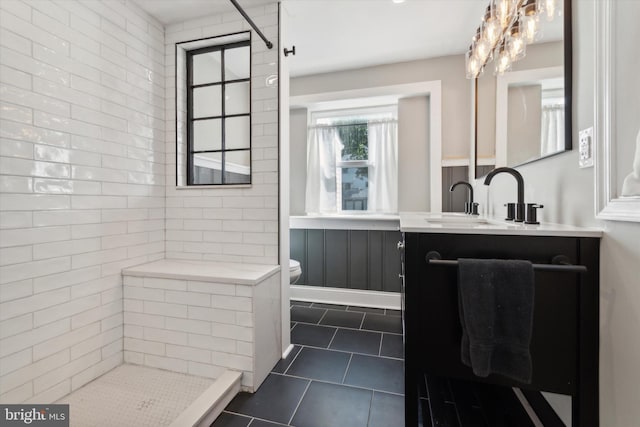 bathroom with toilet, tile patterned flooring, vanity, and tiled shower