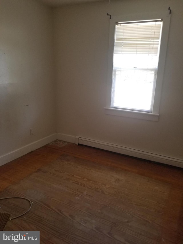 empty room featuring a baseboard radiator and dark wood-type flooring