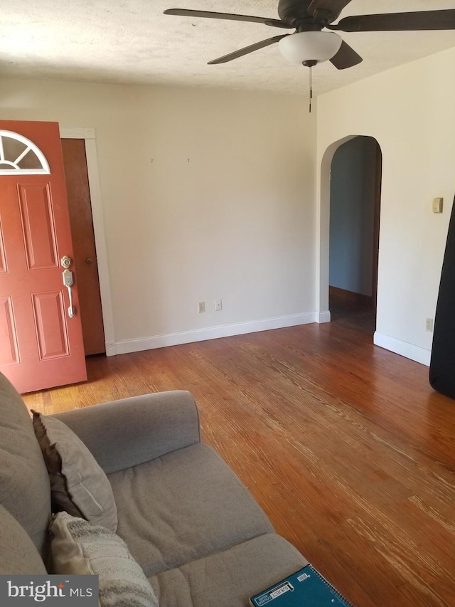 living room featuring ceiling fan, hardwood / wood-style floors, and a textured ceiling