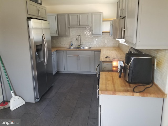 kitchen with sink, butcher block countertops, gray cabinets, appliances with stainless steel finishes, and decorative backsplash