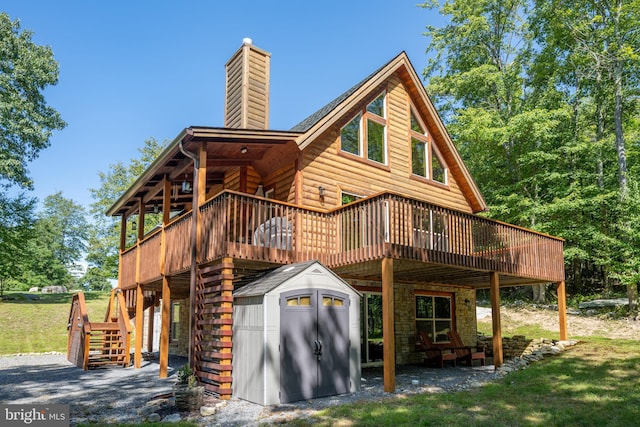 back of house featuring an outbuilding, a chimney, a storage unit, stairway, and log veneer siding