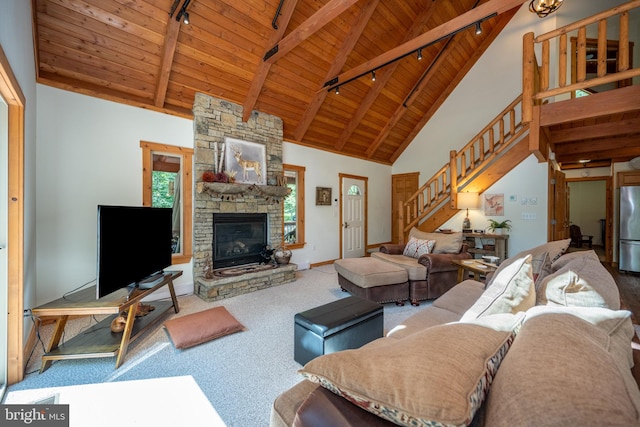 carpeted living room with high vaulted ceiling, rail lighting, a stone fireplace, wooden ceiling, and beam ceiling