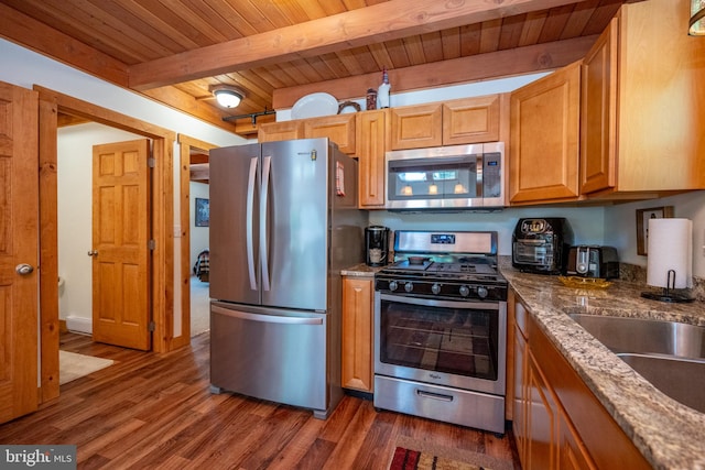 kitchen featuring wooden ceiling, appliances with stainless steel finishes, beamed ceiling, dark stone counters, and dark wood-type flooring