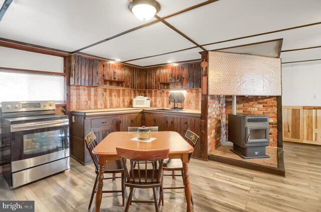 kitchen with light hardwood / wood-style floors, stainless steel electric range, and a wood stove