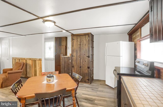 dining room with light wood-type flooring and wooden walls