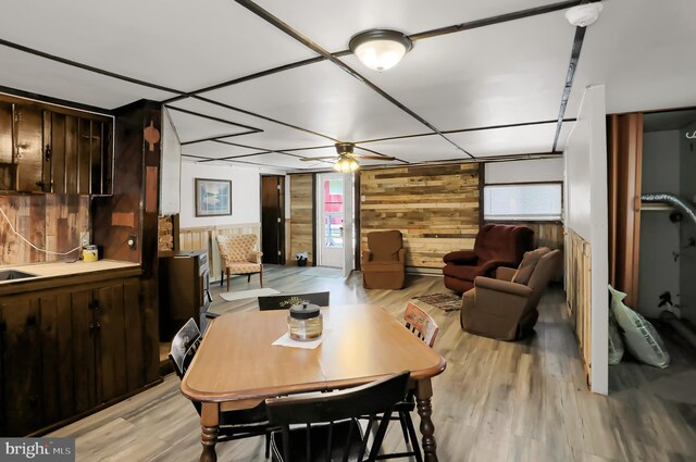 dining room featuring ceiling fan, wooden walls, and light wood-type flooring