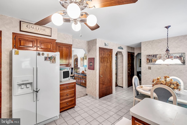 kitchen with pendant lighting, white appliances, light tile patterned floors, and ceiling fan