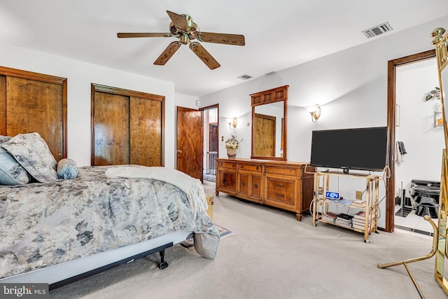 bedroom with multiple closets, ceiling fan, and light colored carpet