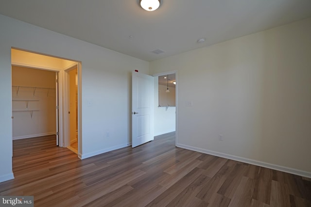 unfurnished bedroom featuring hardwood / wood-style flooring, a closet, and a spacious closet