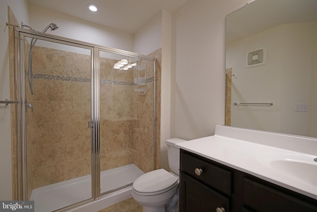 bathroom with a shower with shower door, toilet, vanity, and tile patterned floors