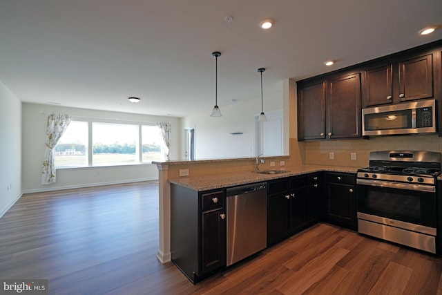 kitchen with kitchen peninsula, appliances with stainless steel finishes, light stone counters, and wood-type flooring