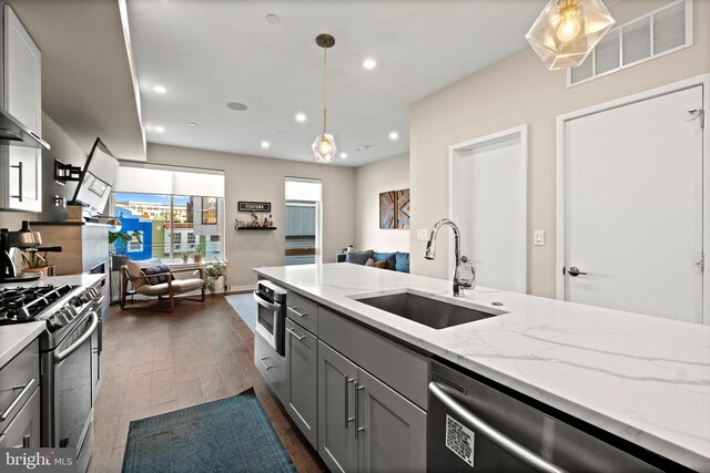 kitchen featuring gray cabinets, pendant lighting, sink, light stone counters, and stainless steel appliances