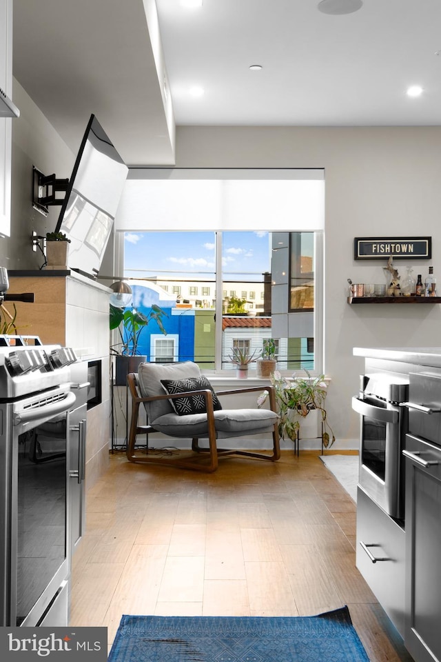 kitchen featuring stainless steel range, hardwood / wood-style floors, and white cabinets