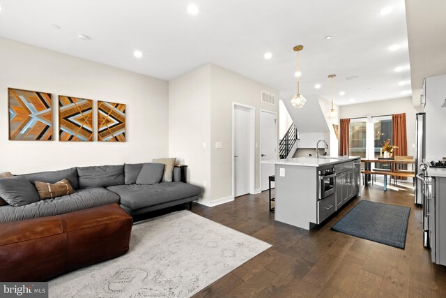 kitchen featuring an island with sink, hanging light fixtures, a kitchen breakfast bar, appliances with stainless steel finishes, and dark hardwood / wood-style flooring