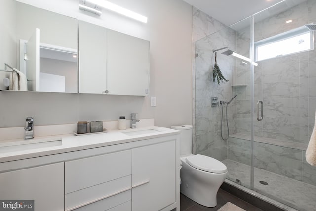 bathroom with a shower with shower door, vanity, and toilet