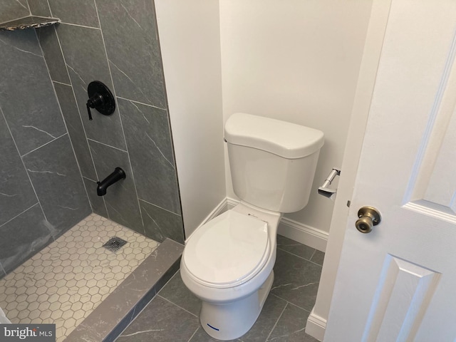 bathroom featuring tiled shower, toilet, and tile patterned floors