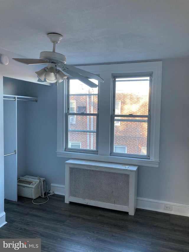 unfurnished bedroom featuring ceiling fan, hardwood / wood-style flooring, a closet, and radiator heating unit