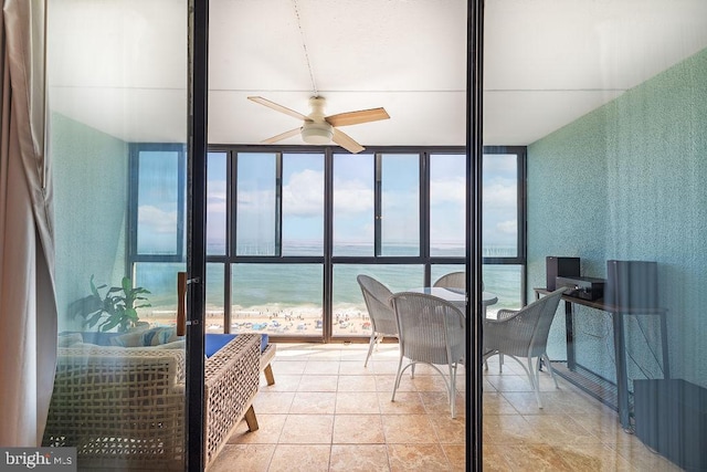 sunroom / solarium with ceiling fan, a beach view, and a water view