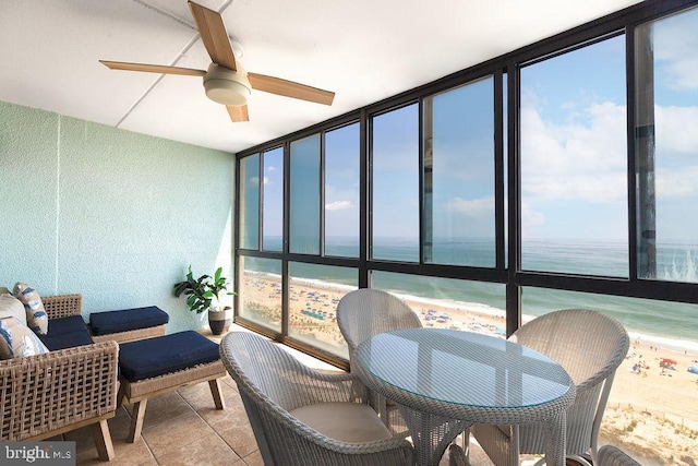 sunroom / solarium with ceiling fan, a view of the beach, and a water view