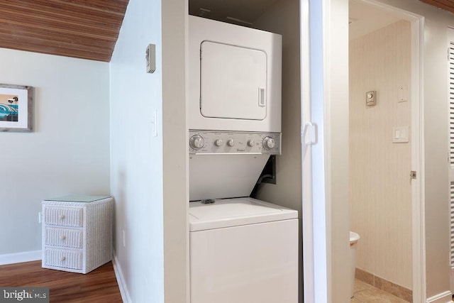 washroom featuring hardwood / wood-style flooring, stacked washer / drying machine, and wooden ceiling