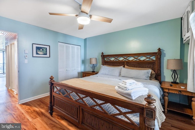 bedroom featuring a ceiling fan, a closet, baseboards, and wood finished floors