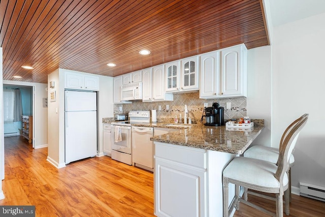 kitchen with glass insert cabinets, white cabinets, a sink, white appliances, and a peninsula