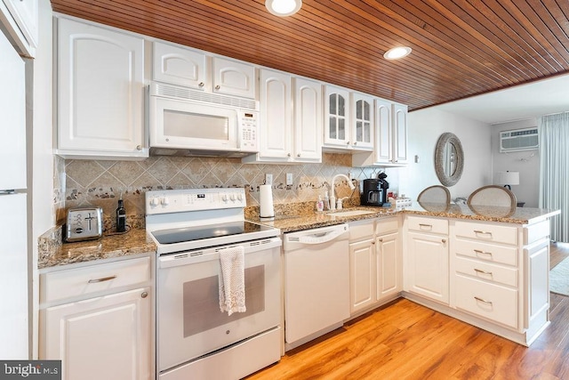 kitchen with glass insert cabinets, white cabinetry, a sink, white appliances, and a peninsula