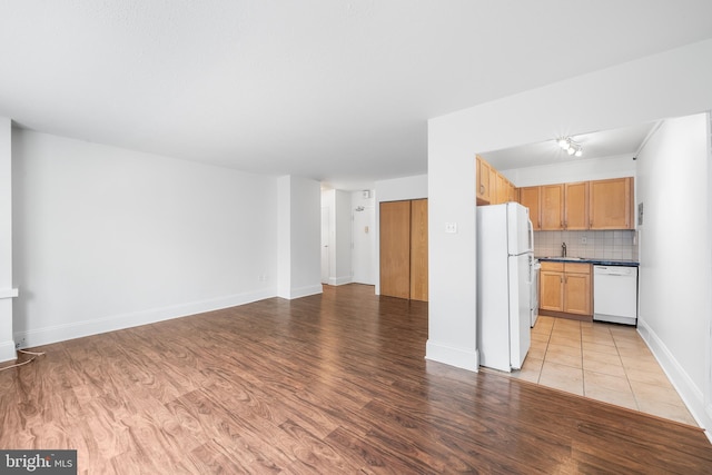 kitchen featuring white appliances, light wood-style floors, open floor plan, backsplash, and dark countertops