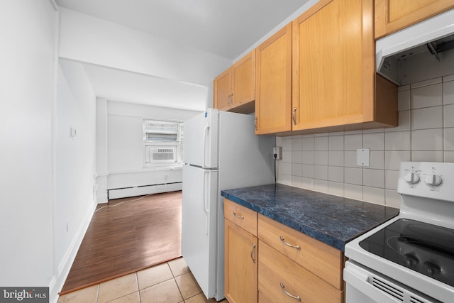 kitchen featuring tasteful backsplash, a baseboard radiator, dark countertops, white appliances, and under cabinet range hood