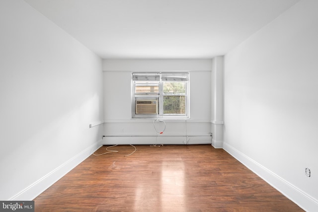 empty room with cooling unit, baseboards, baseboard heating, and wood finished floors