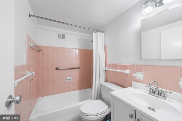 bathroom with visible vents, toilet, shower / bath combo with shower curtain, vanity, and tile walls