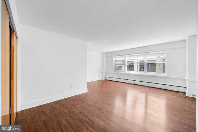 unfurnished living room featuring baseboards, a baseboard heating unit, and wood finished floors