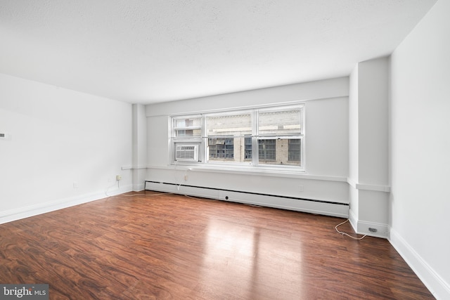 unfurnished room with a baseboard radiator, baseboards, dark wood finished floors, and a textured ceiling