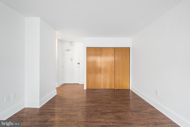 unfurnished bedroom with dark wood-type flooring, a closet, and baseboards