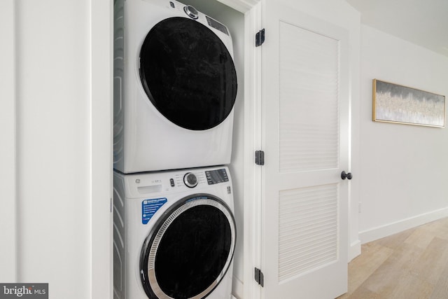 clothes washing area featuring light hardwood / wood-style flooring and stacked washing maching and dryer