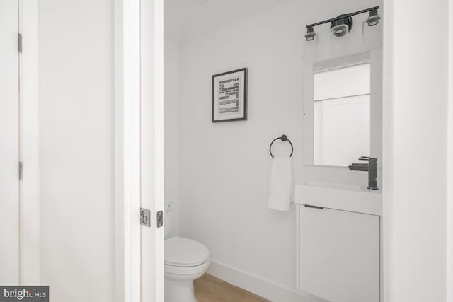 bathroom with toilet, vanity, and wood-type flooring