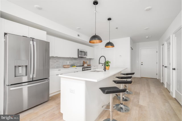 kitchen with decorative backsplash, white cabinetry, appliances with stainless steel finishes, light hardwood / wood-style floors, and sink