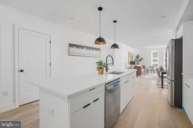 kitchen with stainless steel appliances, light hardwood / wood-style flooring, sink, pendant lighting, and white cabinets