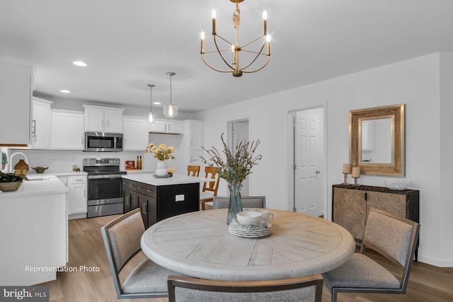 dining area featuring light wood-type flooring, baseboards, an inviting chandelier, and recessed lighting