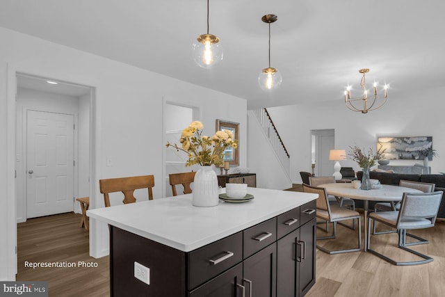 kitchen with a center island, light countertops, hanging light fixtures, open floor plan, and light wood-type flooring