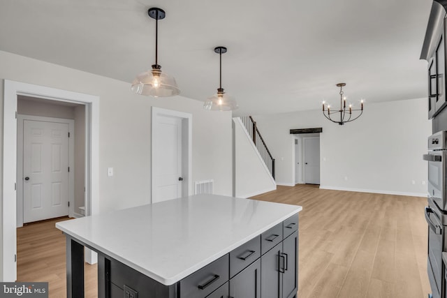 kitchen featuring a center island, decorative light fixtures, light wood finished floors, gray cabinets, and light countertops