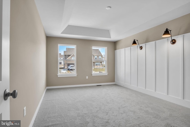 carpeted empty room with a raised ceiling and baseboards