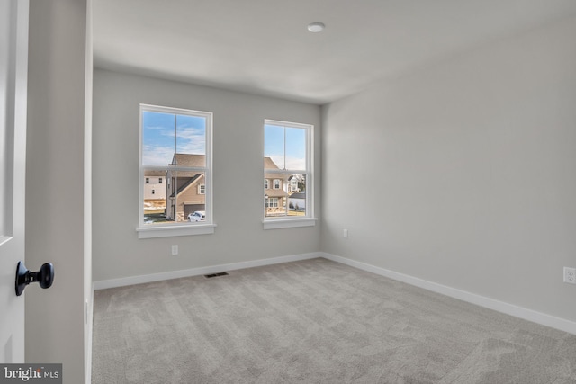 empty room featuring baseboards, visible vents, and light colored carpet