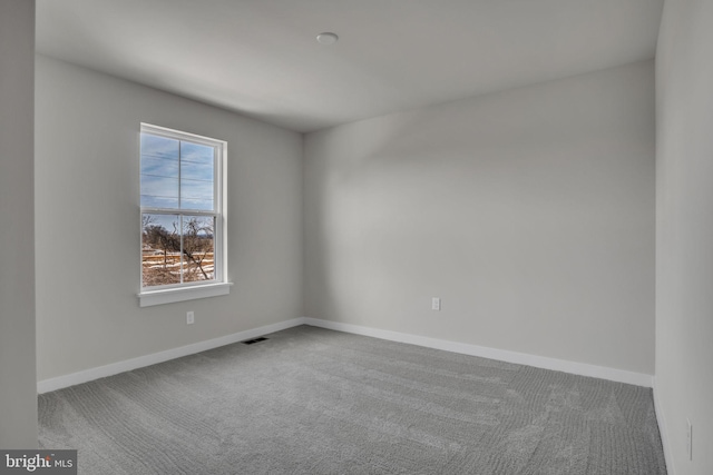 spare room with carpet floors, visible vents, and baseboards