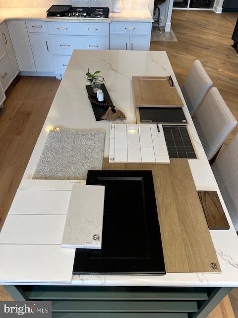 kitchen with black gas stovetop, white cabinetry, dark hardwood / wood-style floors, and a center island