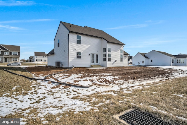 snow covered property featuring a residential view and central AC unit