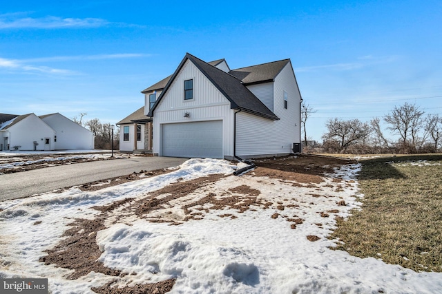 snow covered property with a shingled roof and driveway