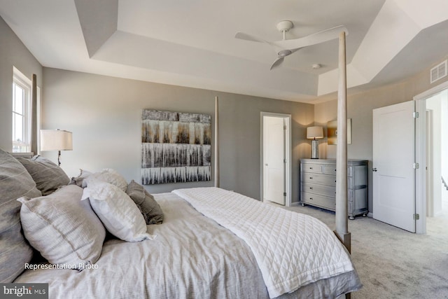 bedroom with a tray ceiling, a ceiling fan, and light colored carpet