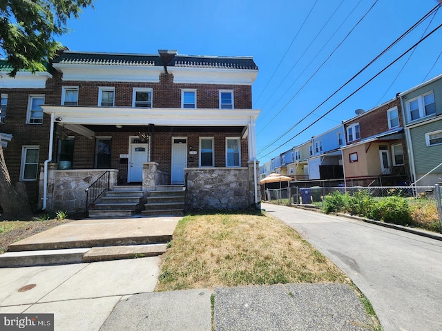 multi unit property with a tiled roof, a porch, a residential view, and brick siding